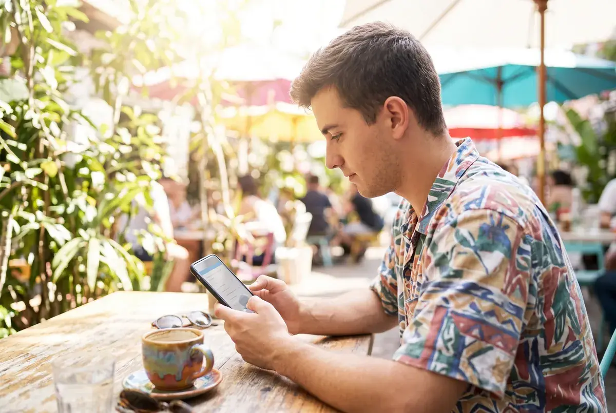A respondent completing a mobile survey at a sunny cafe, as part of quantitative recruitment services