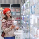 Young woman choosing a medication in pharmacy store.